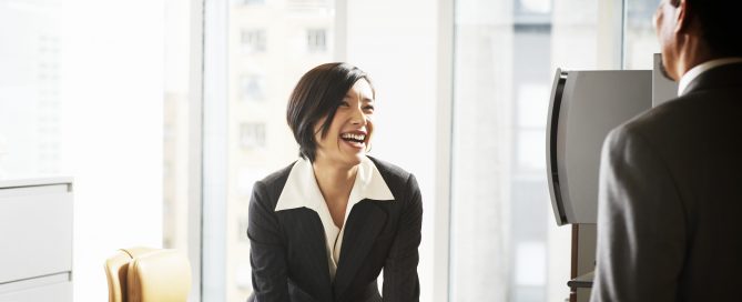 Businesswoman at desk smiiling at businessman