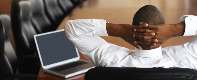businessman relaxing in an empty conference room with a laptop in front of him