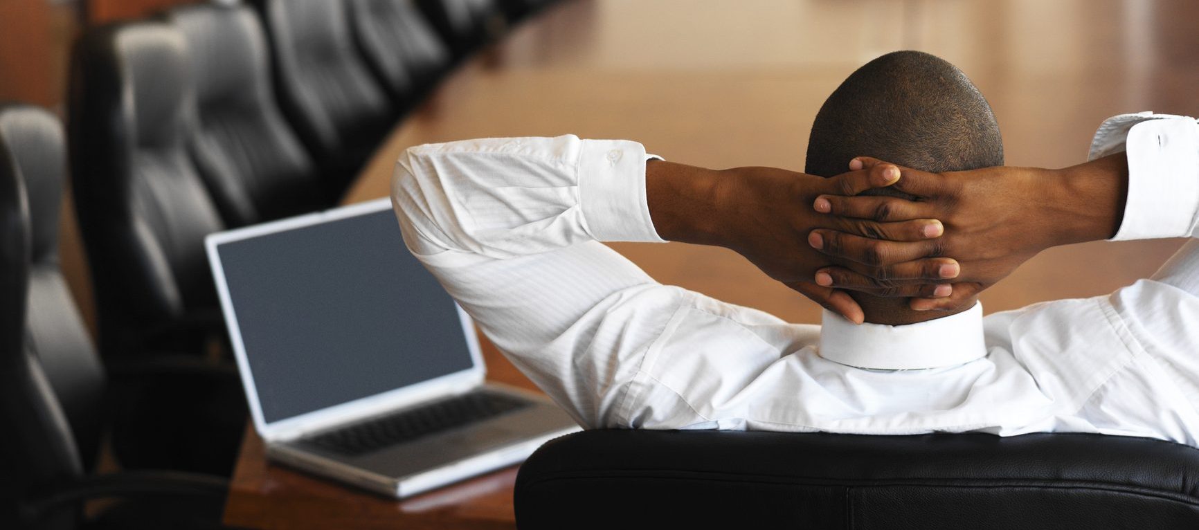 businessman relaxing in an empty conference room with a laptop in front of him