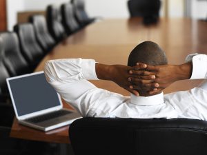 businessman relaxing in an empty conference room with a laptop in front of him