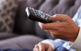 Close Up Of Man Sitting On Sofa Holding TV Remote