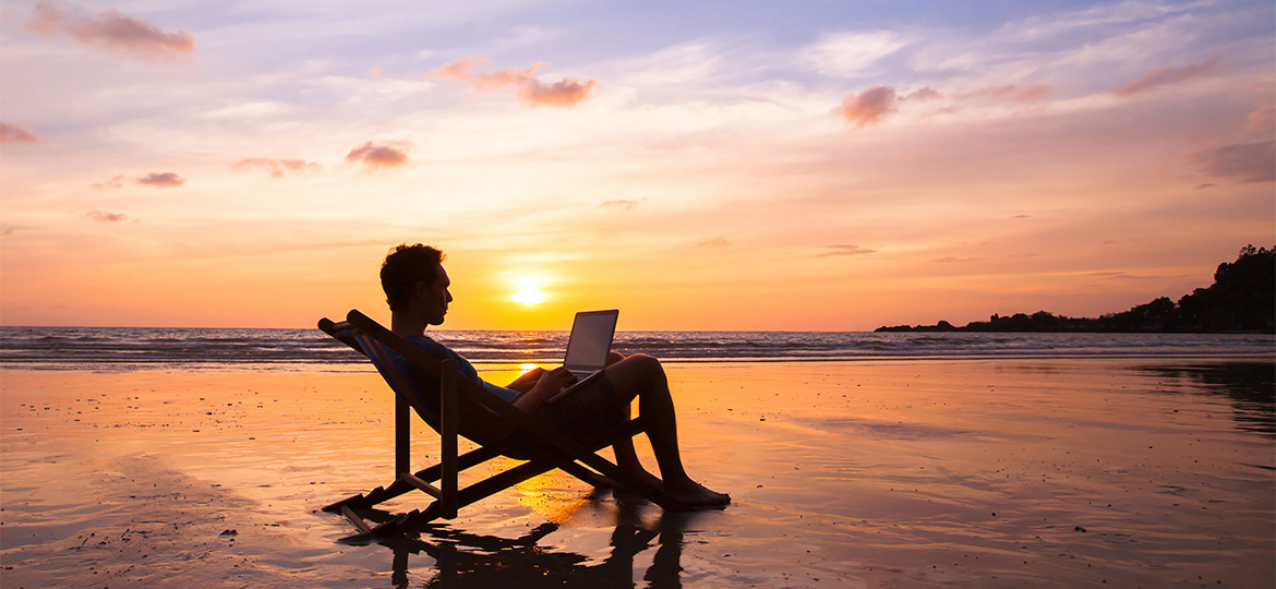 Man working on laptop at beach