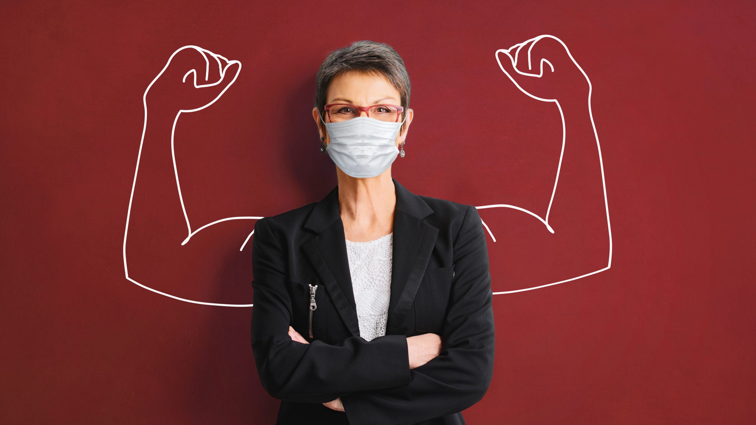 worker in mask standing in front of a drawing of strong arms